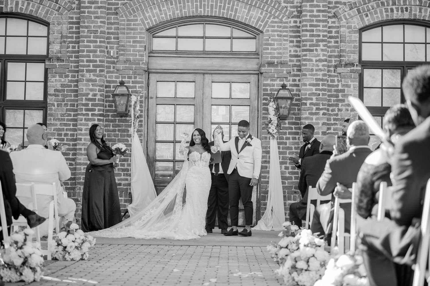 Panoramic view of wedding ceremony setup against rustic brick architecture.