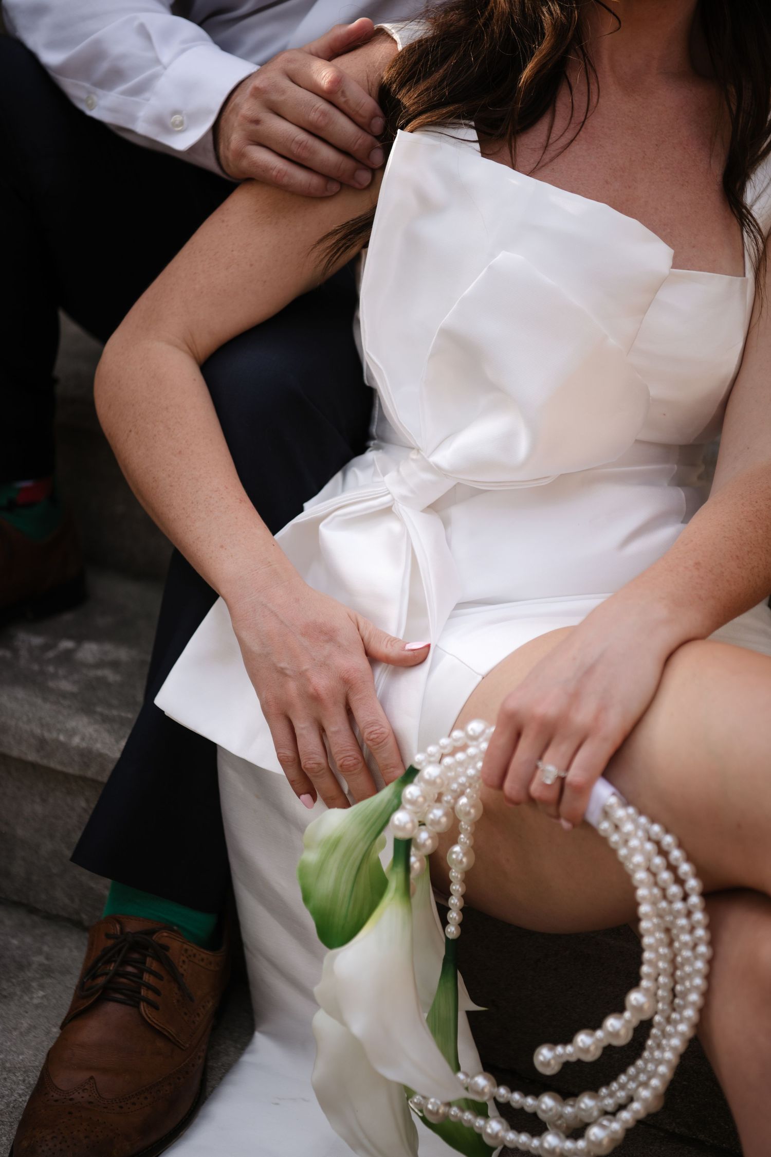 Close-up sequence of white wedding dress with pearl necklace and green stem detail against dark background.
