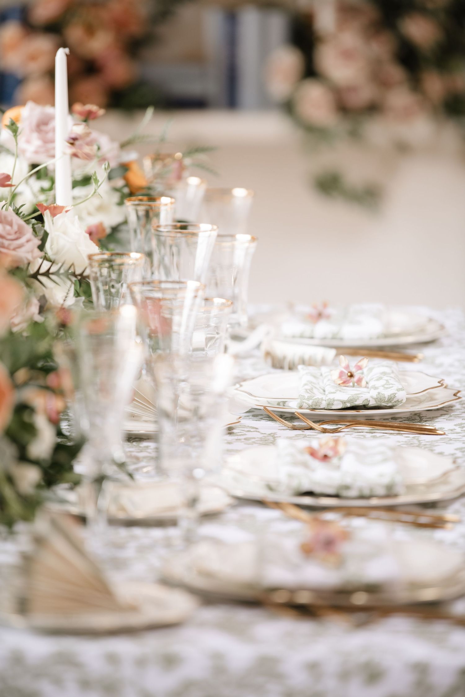 Close-up of elegant table settings with crystal glasses and white plates on a lace tablecloth.