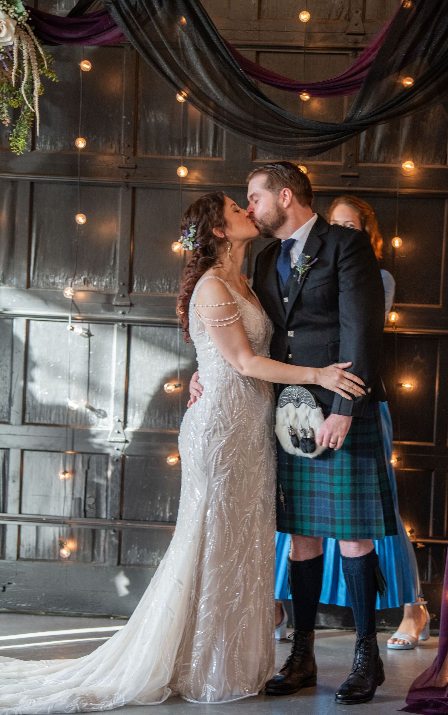 Romantic moment at Scottish wedding with bride in lace gown and groom in traditional kilt.