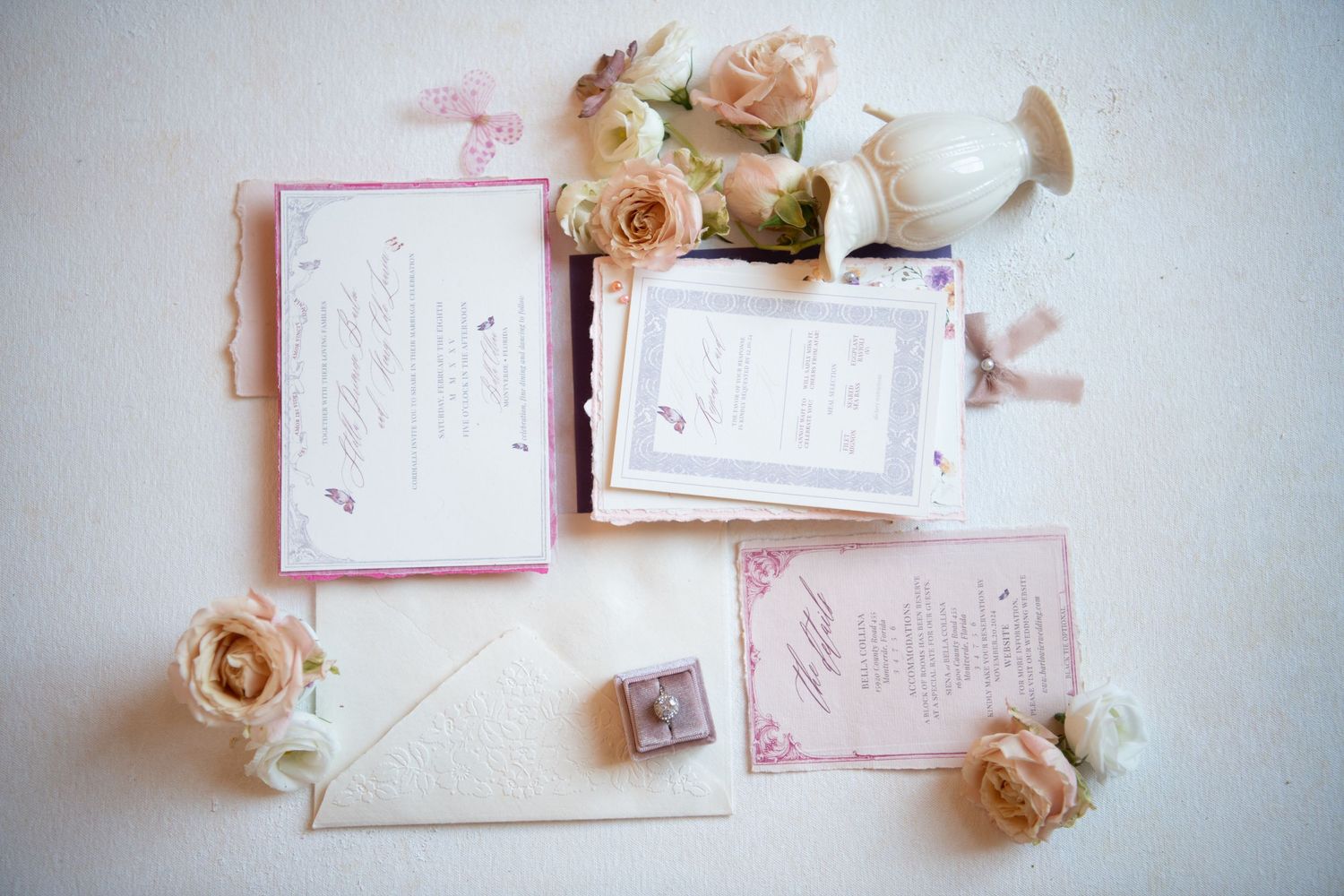 Wedding invitation suite in pink and white with delicate floral accents.