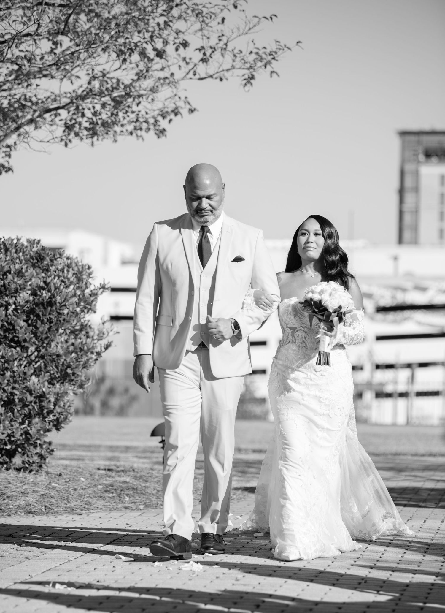 A black and white photo of a couple walking together during their outdoor wedding ceremony.