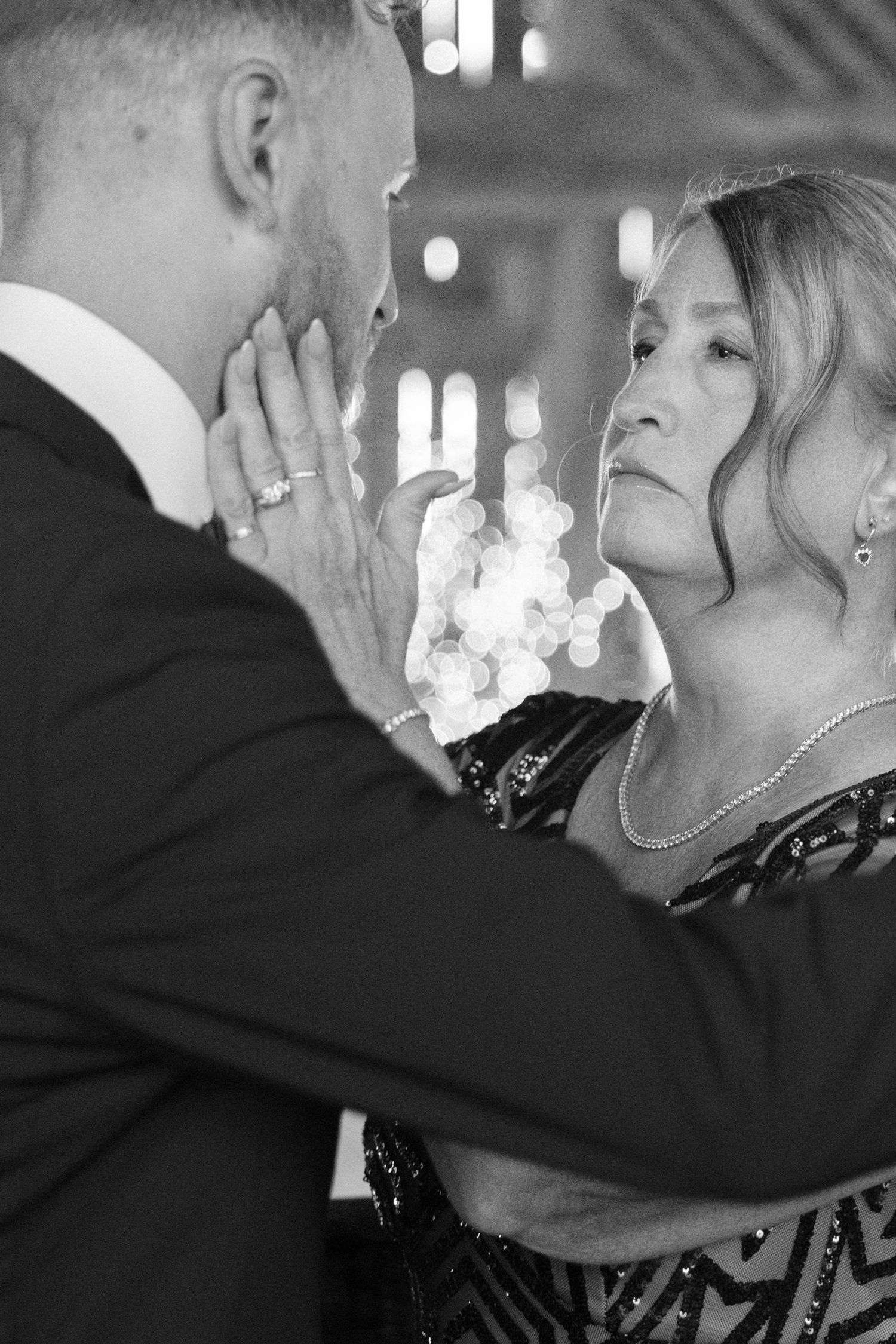 Emotional black and white photo of groom dancing with his mother at wedding reception.