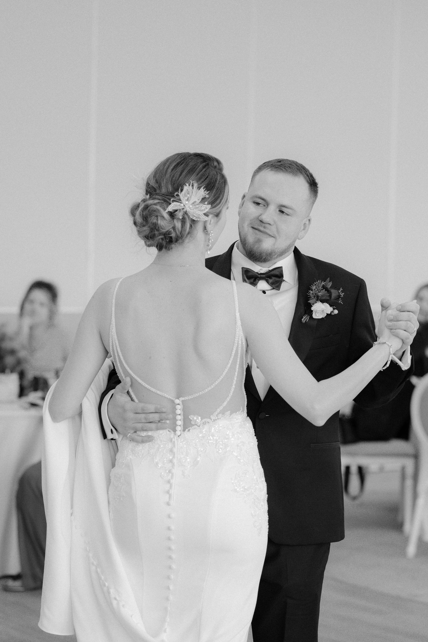 Black and white photo of bride and groom sharing their first dance, showcasing the open back wedding gown.