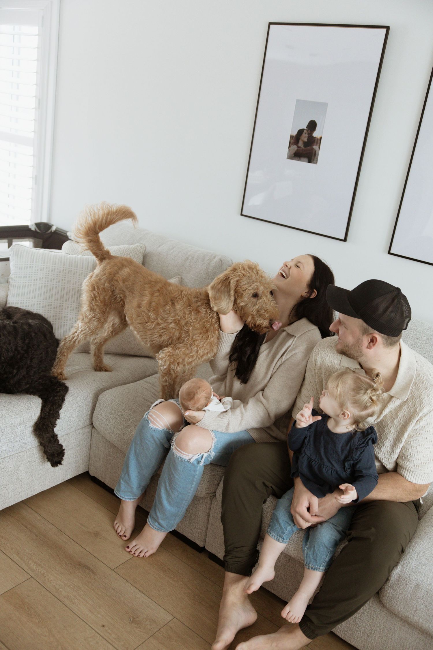 Happy family with two children and golden doodle dog relaxing together on white sofa.