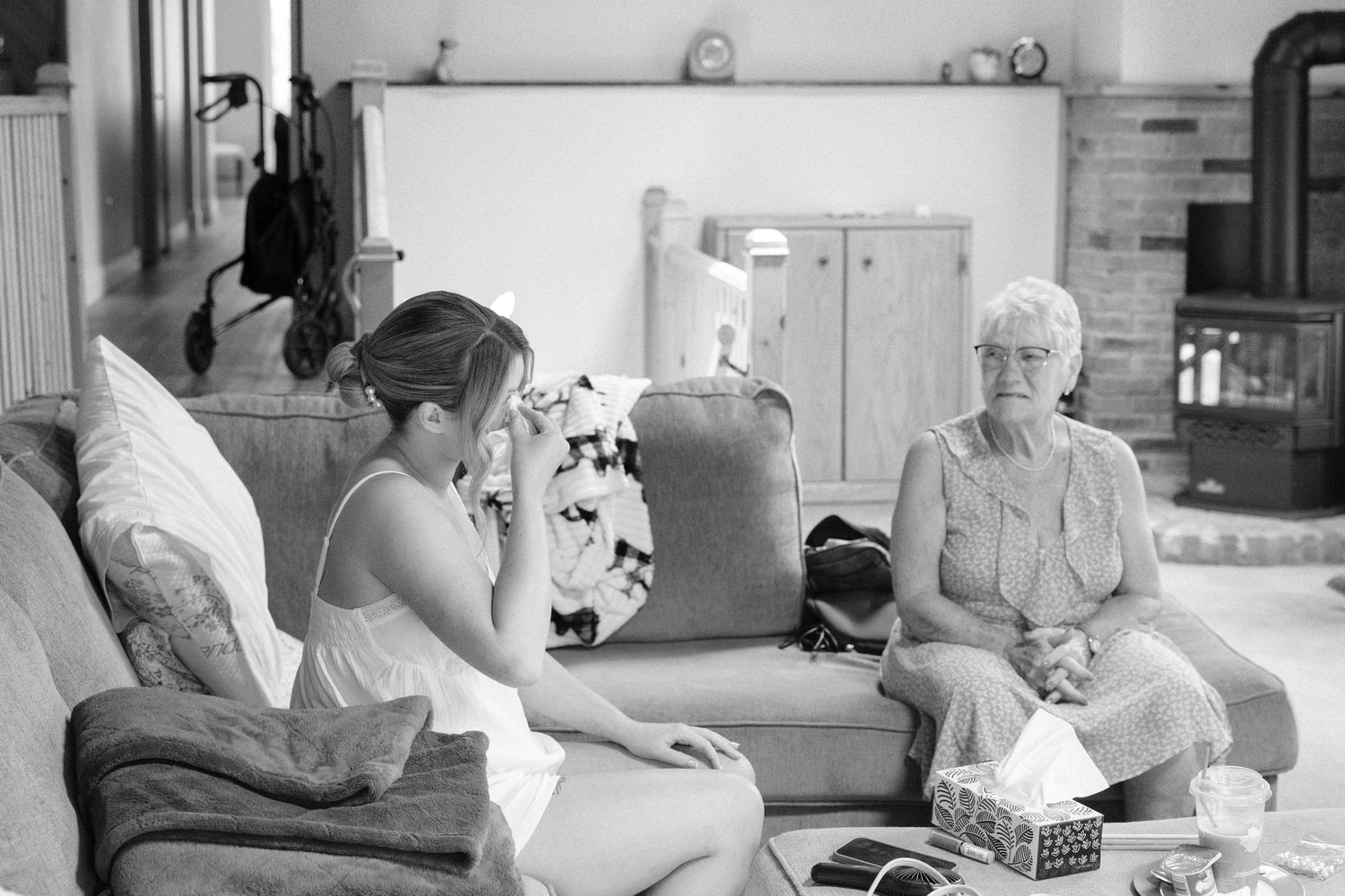 Black and white candid photo of young woman and elderly grandmother sitting together on sofa before wedding.