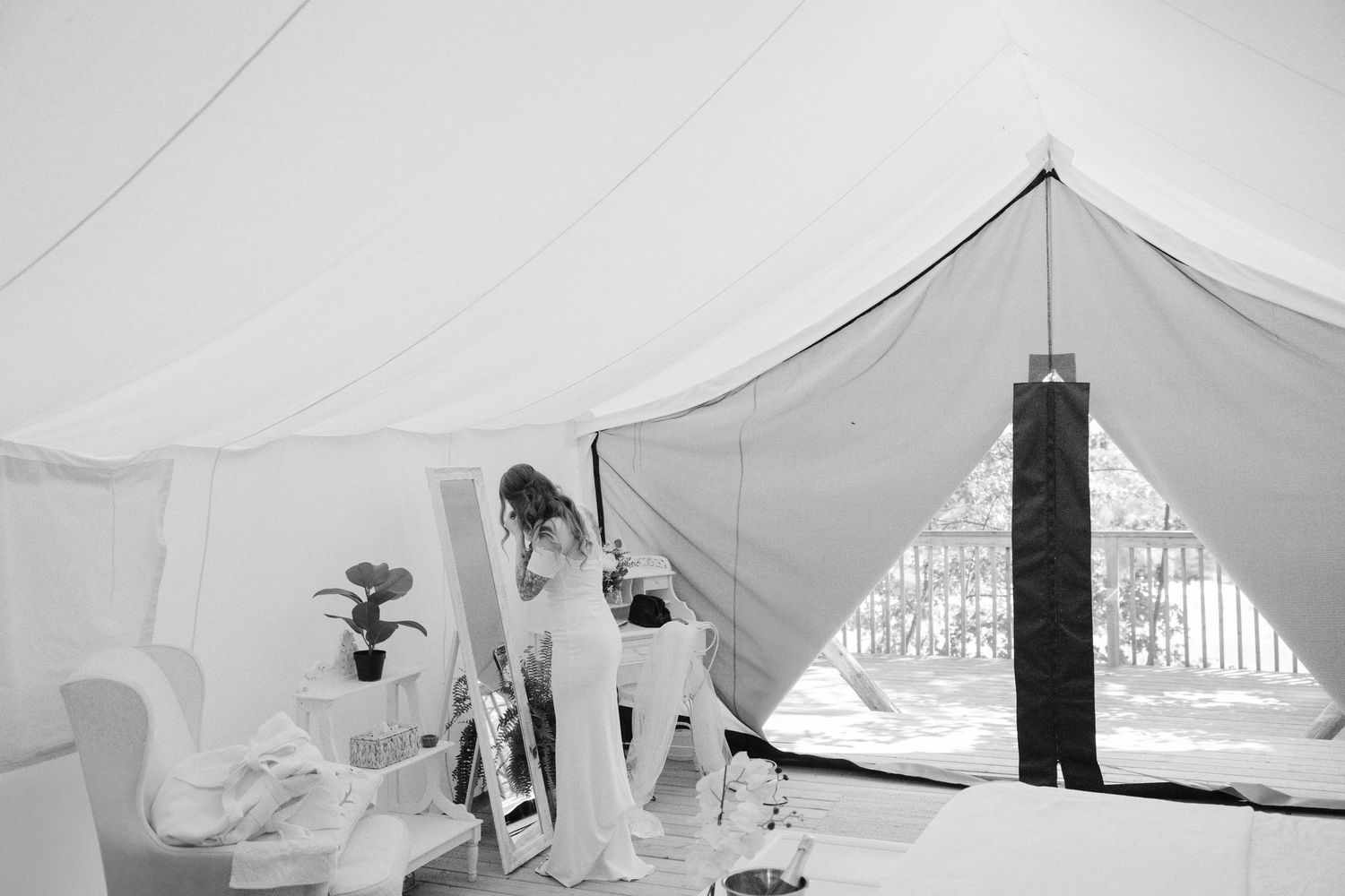 Black and white photo of bride getting ready inside an elegant white tent bridal suite.