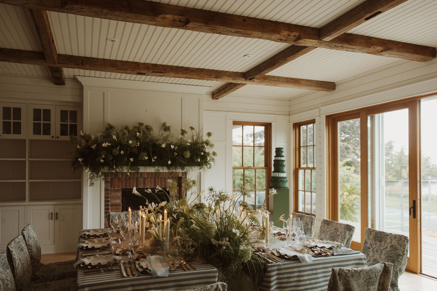 Elegant wedding reception room with rustic wood beams, floral centerpiece, and candlelit dining table.