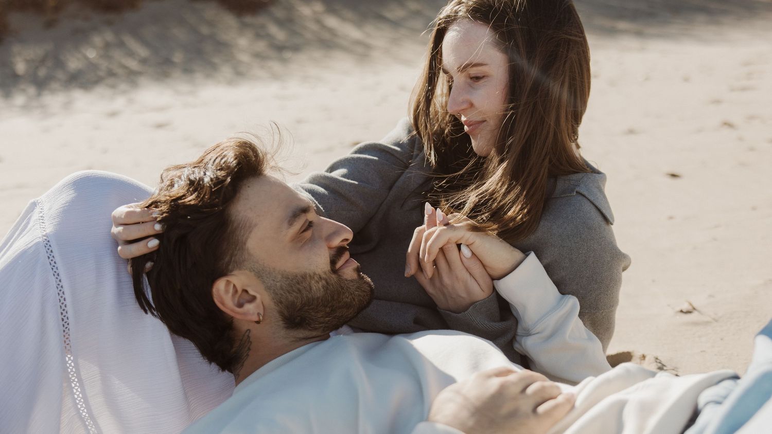 Romantic couple sharing a tender moment together while relaxing on a sandy beach.