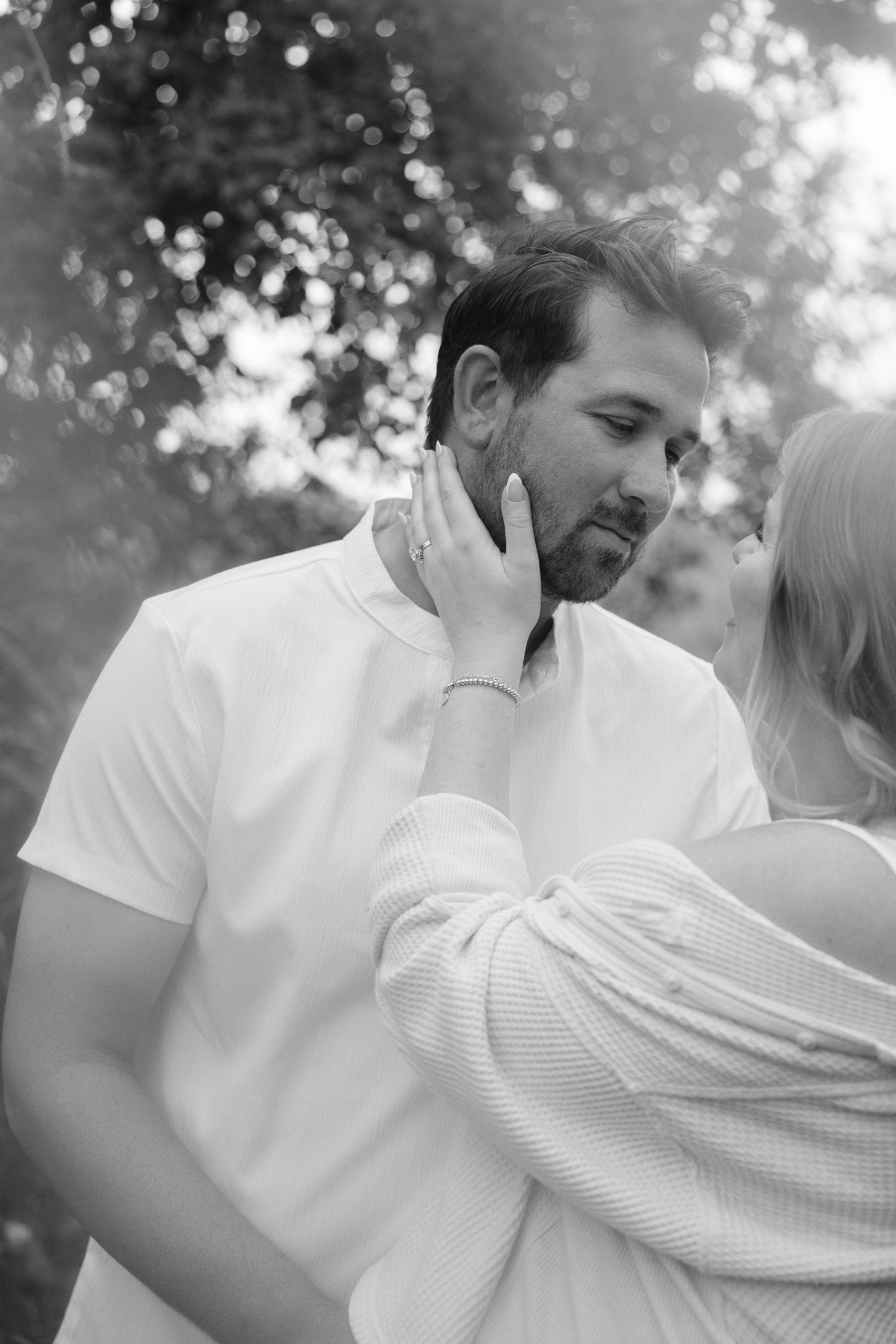 Black and white photo of a woman tenderly touching a bearded mans face.