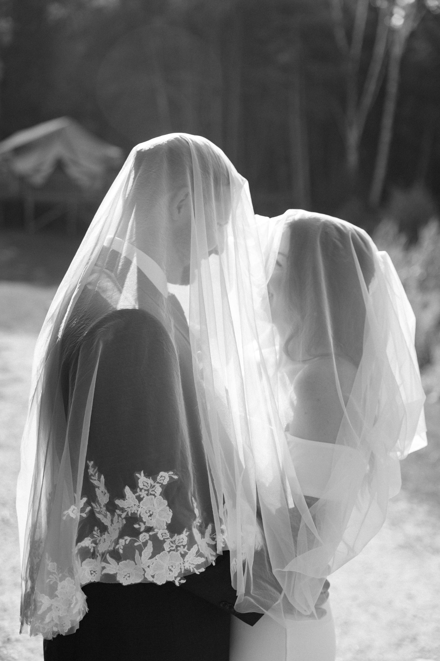 Romantic black and white photo of bride and groom sharing a kiss hidden beneath the bridal veil.