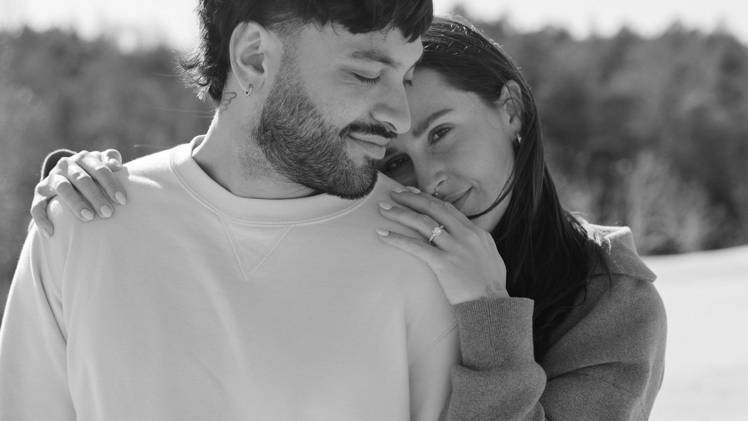 Intimate black and white couple portrait with woman resting head on mans shoulder in snow.