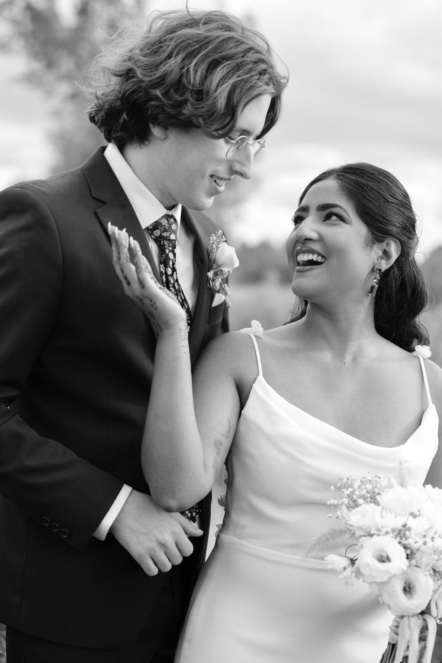 Black and white portrait of laughing bride and groom sharing a joyful moment on their wedding day.