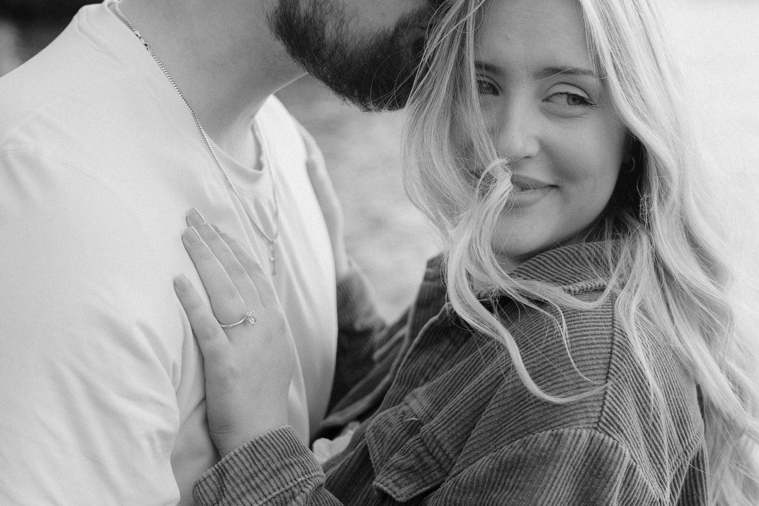 Black and white close-up of couple embracing romantically outdoors.