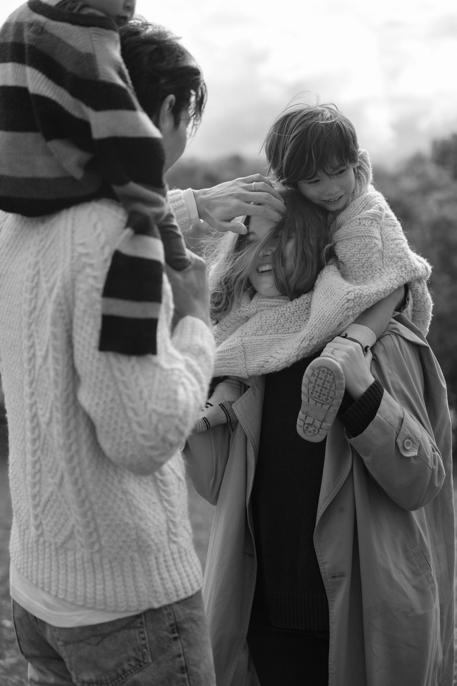Black and white photo of family with child being held outdoors.