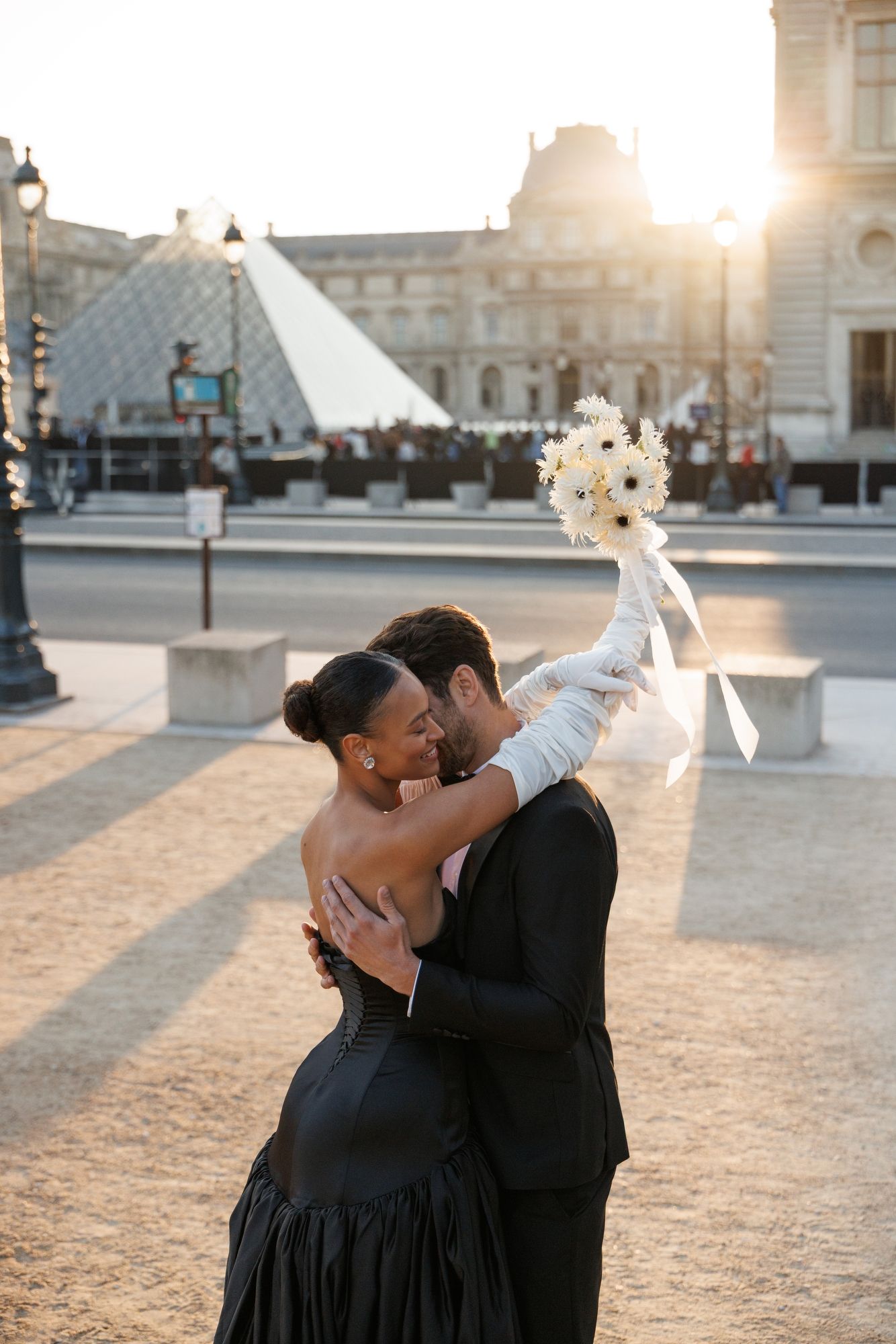 A romantic couple dances together at sunset in front of the Louvre Museum in Paris. Paris Louvre