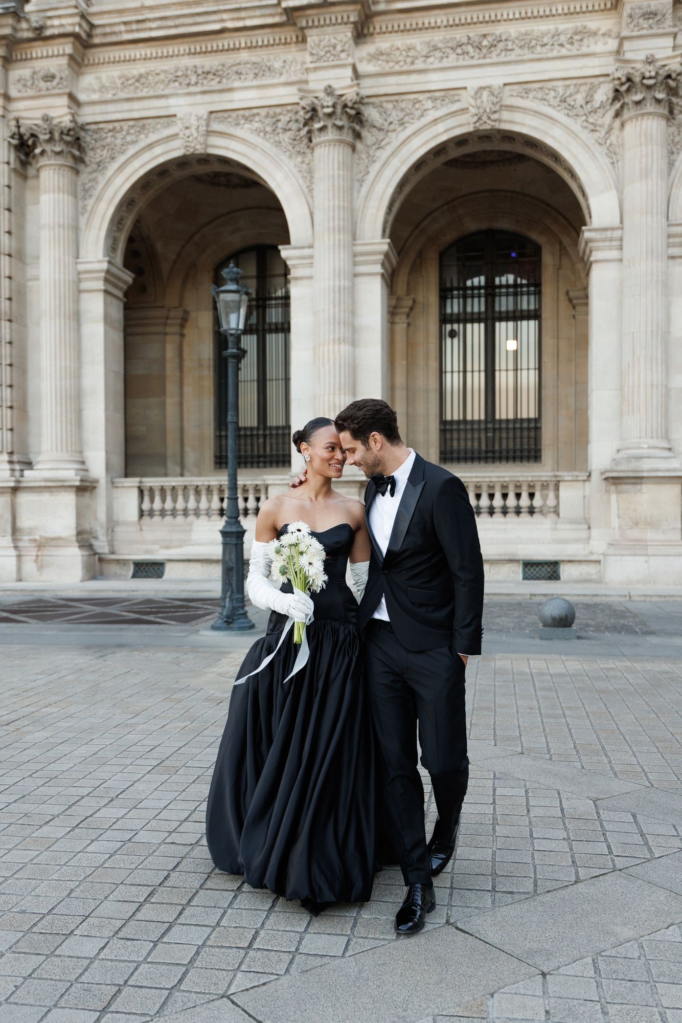 Elegant couple dances on stone courtyard surrounded by classical architecture. Paris Louvre