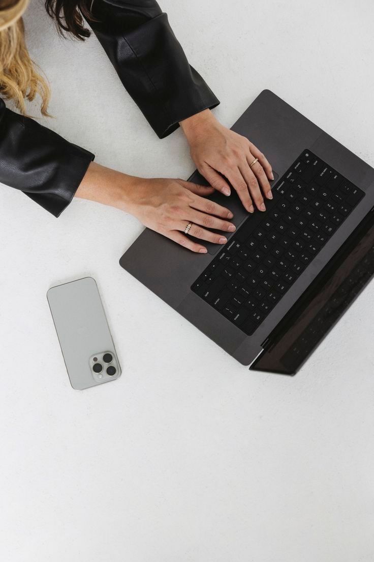 Hands typing on a black laptop keyboard shown in multiple angles on a white desk with an iPhone visible in the last frame.