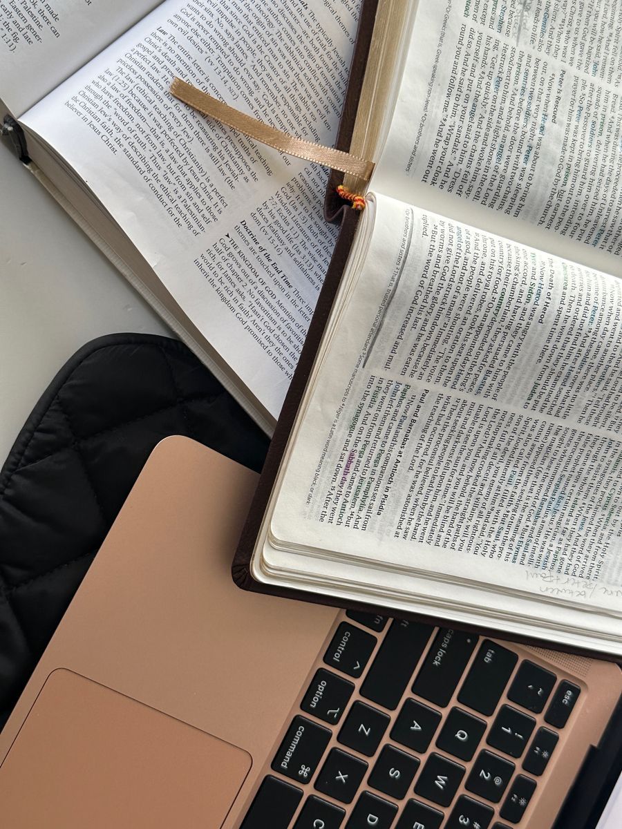 Open book resting on a laptop keyboard in natural lighting.