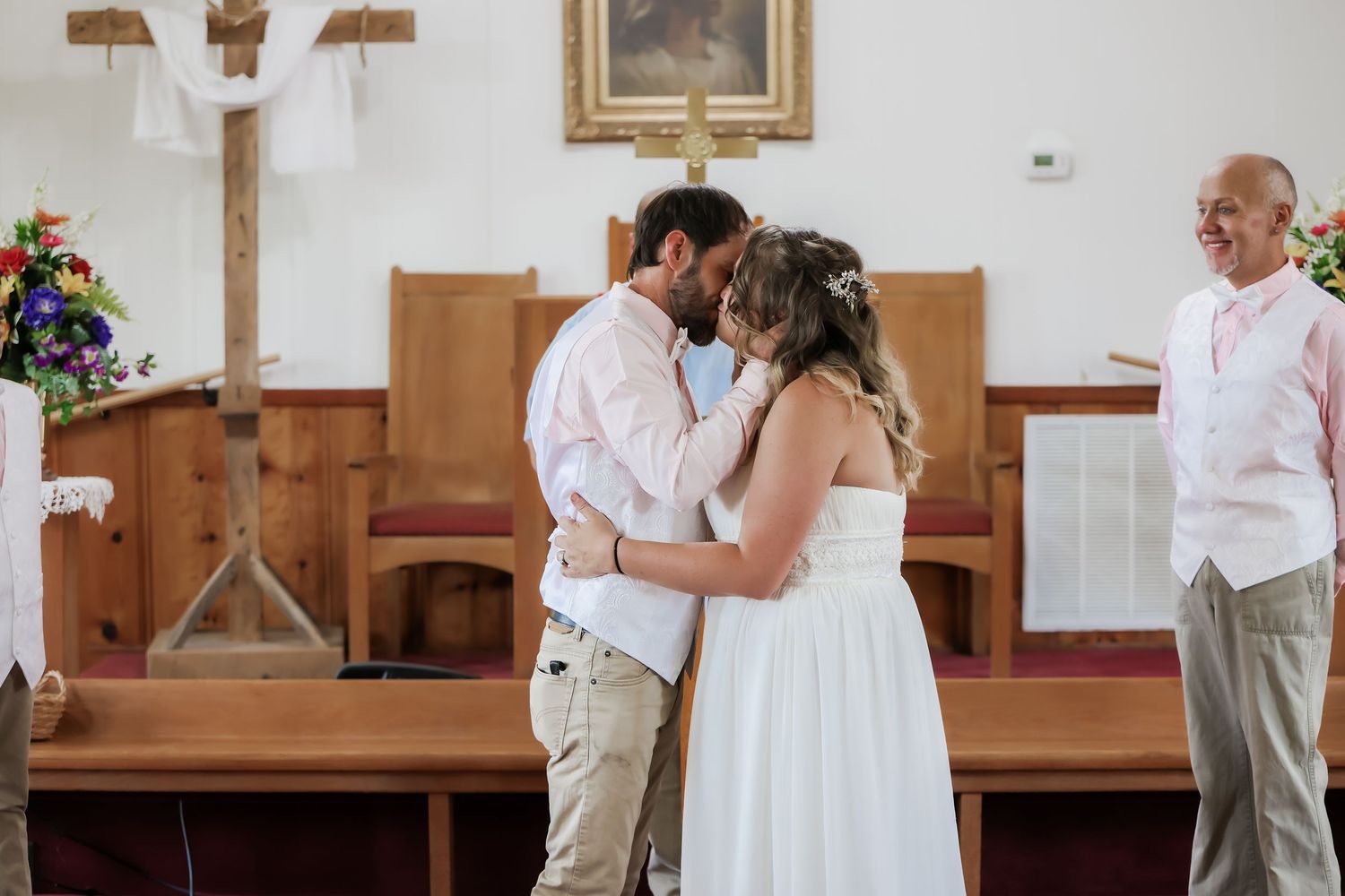 A bride and groom share their first kiss at the altar in a charming rustic church during their wedding ceremony.