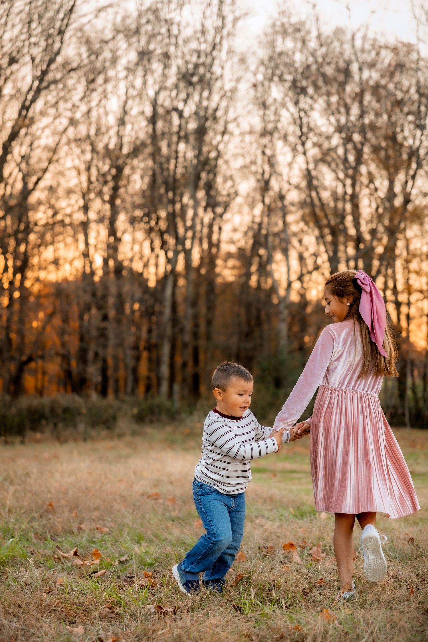 Children holding hands and playing ring around the Rosie during a joyful outdoor childhood photography session.