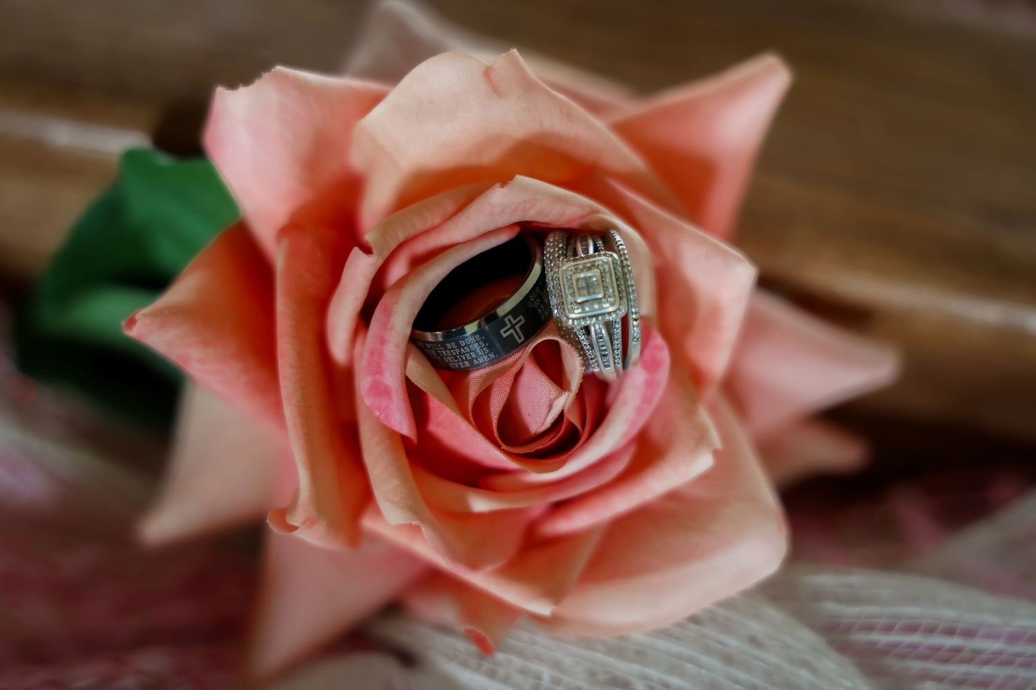 Wedding rings nestled inside a pink rose bloom, featuring a diamond engagement ring and matching band.