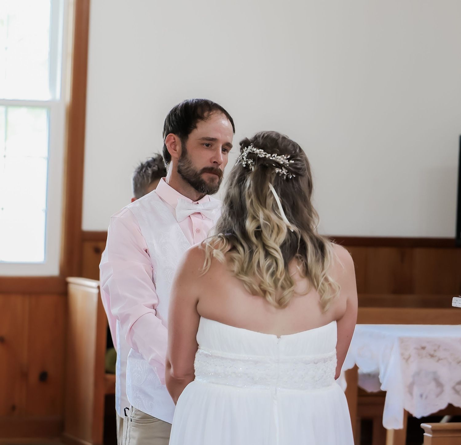 A bride and groom exchange vows at the altar during an intimate indoor wedding ceremony.