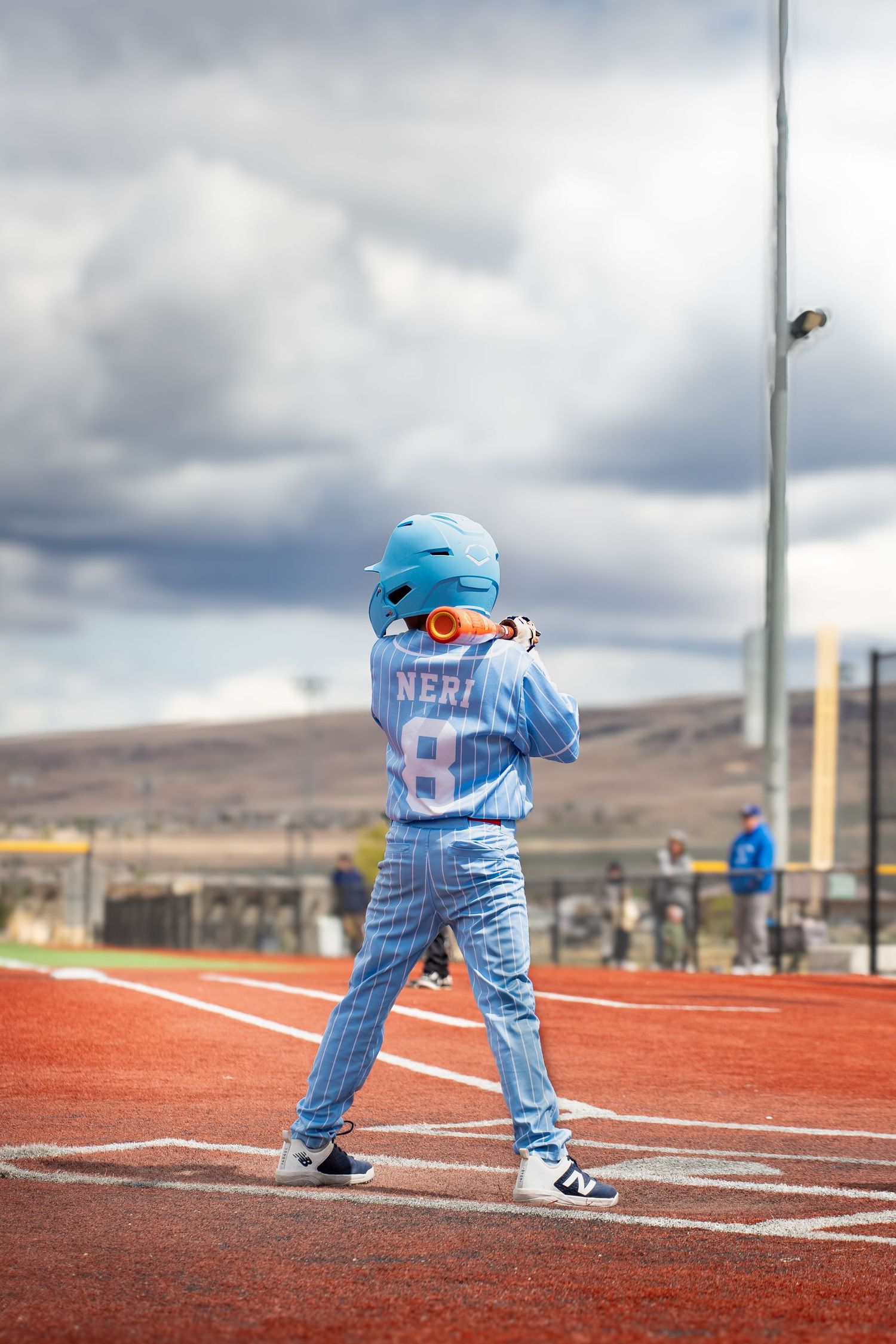 Youth baseball player named Neri number 8 stands in batting stance wearing light blue pinstripe uniform on field.