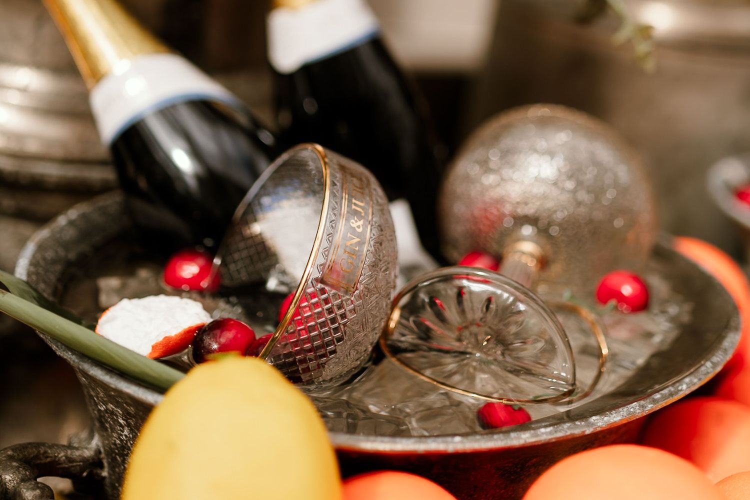 Elegant wedding table display with champagne bottle, silver ornaments, and red berries on decorative tray.