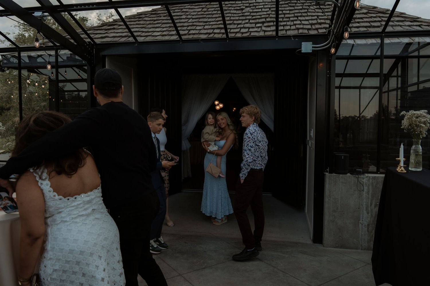 Guests mingling at an elegant outdoor wedding reception venue with string lights and a decorative entrance.