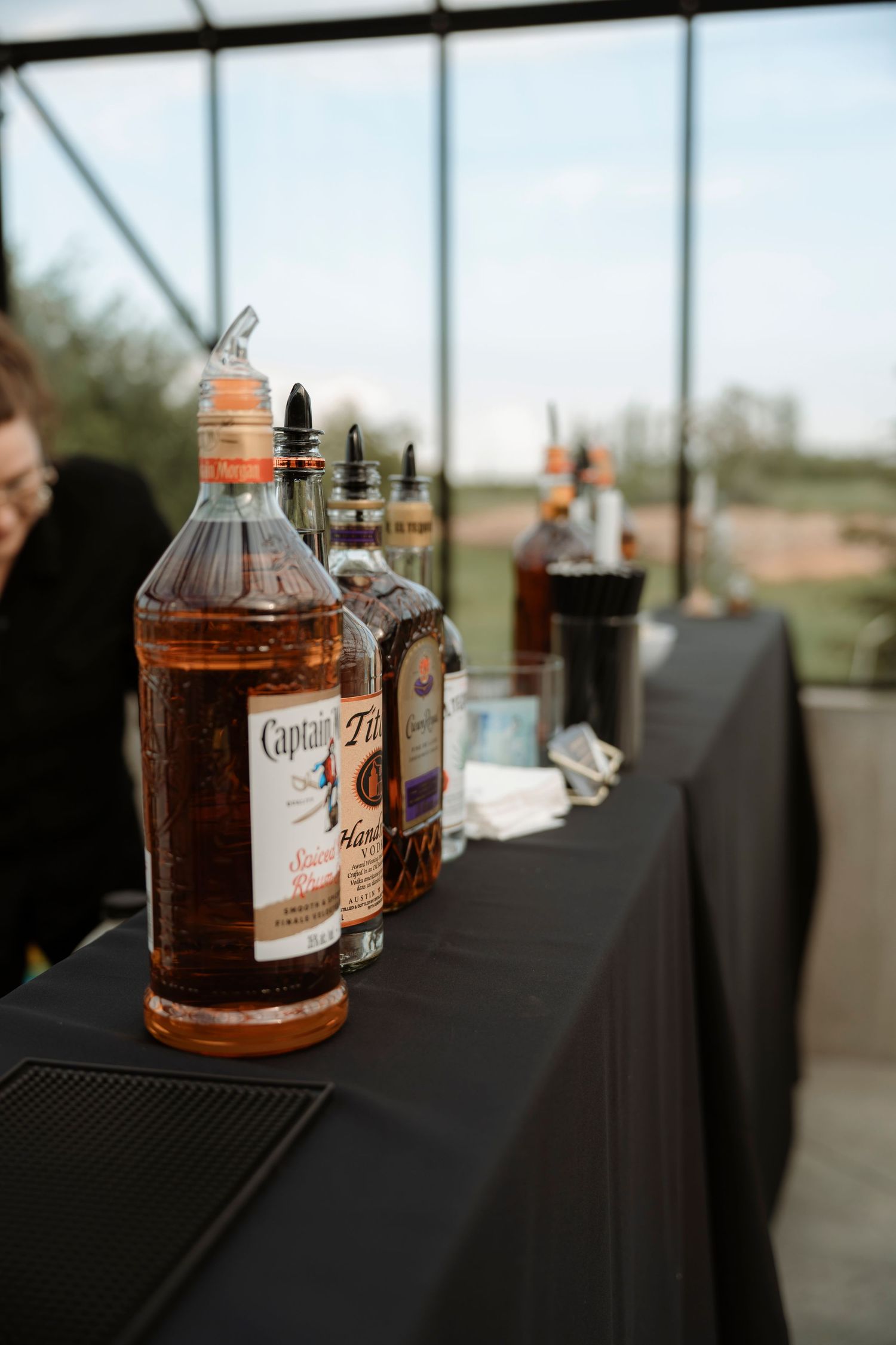 Captain Morgan rum bottles lined up on a black draped bar table at an outdoor event venue.