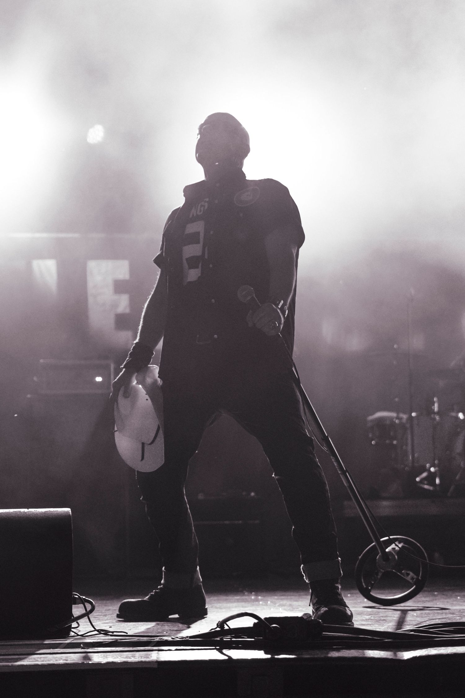 Black and white silhouette of a rock musician holding a guitar on a smoky concert stage.