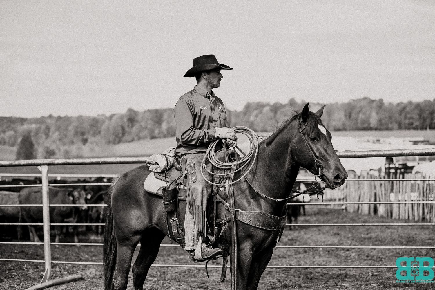 Black and white photograph of a mounted rider in western gear at a ranch.