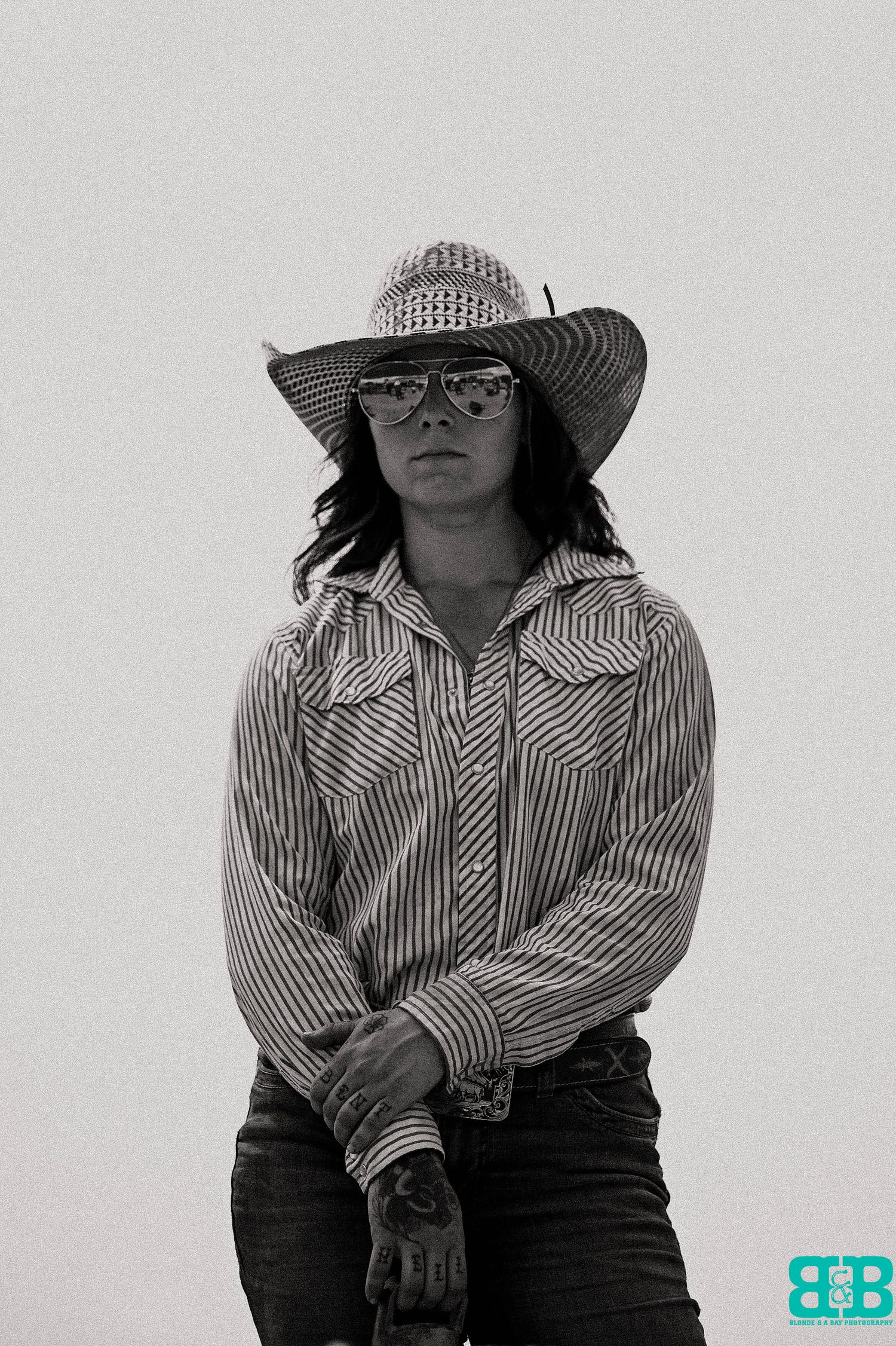 Portrait in black and white of someone wearing a striped western shirt and wide-brimmed hat.