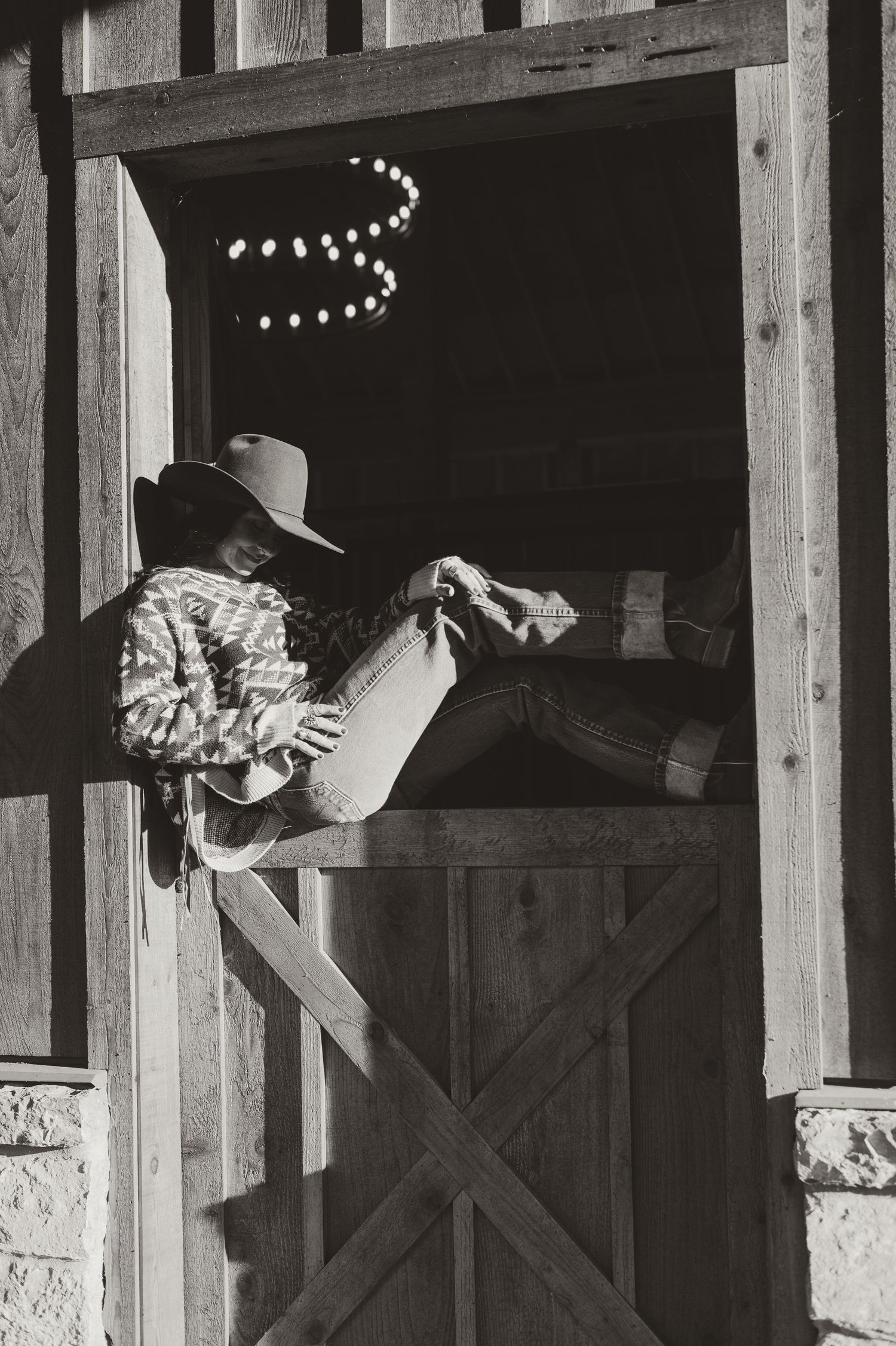 Cowboy hats and western attire silhouetted in a rustic barn setting with string lights.
