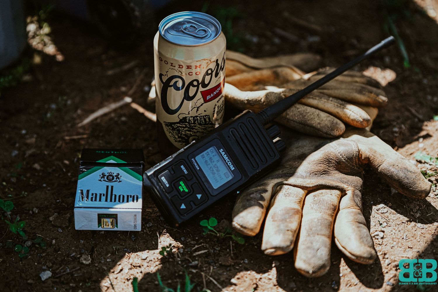 Work gloves and cigarette pack rest on weathered wood surface in natural lighting.