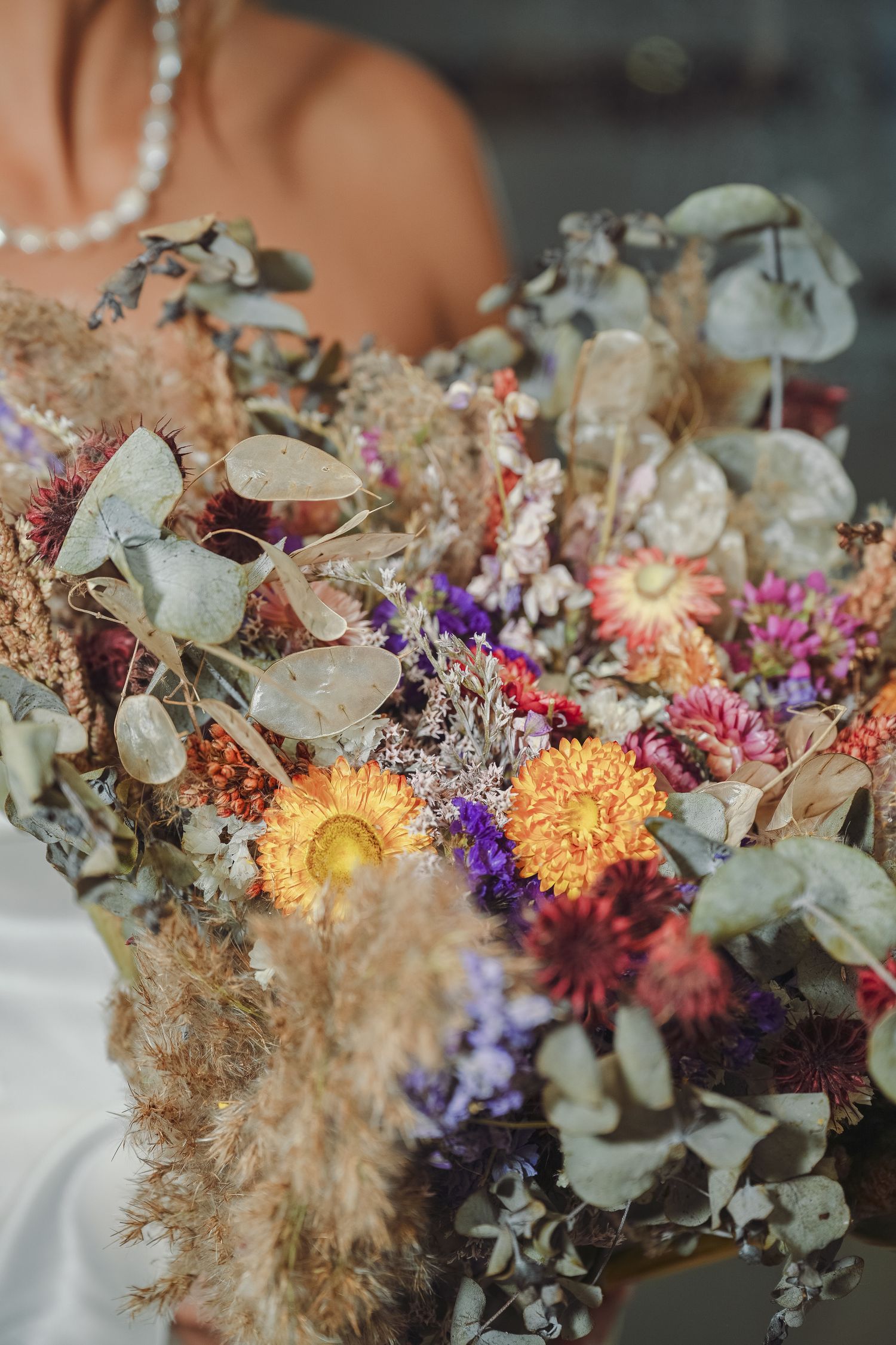 Colorful dried wedding bouquet with yellow, purple and pink flowers mixed with eucalyptus.
