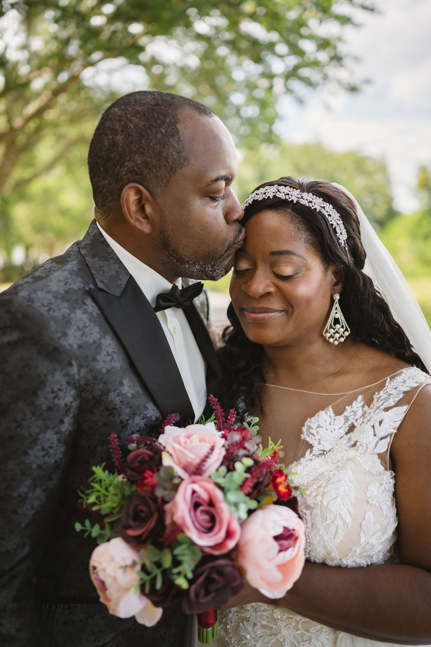 Romantic wedding portrait with bride holding pink and burgundy bouquet.