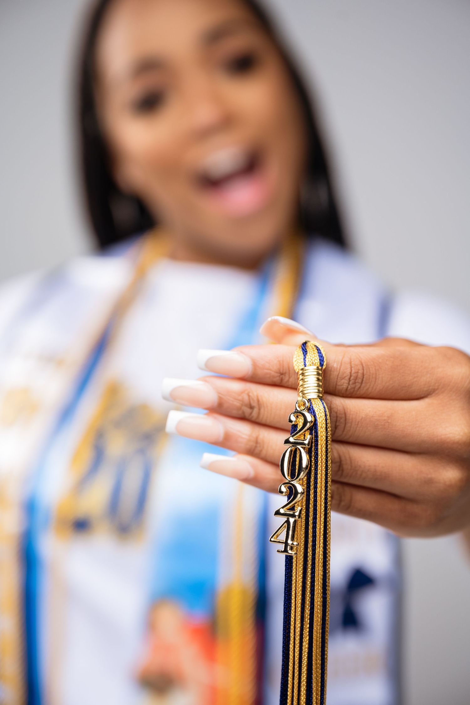 Close-up of hands holding graduation tassel with blurred background.