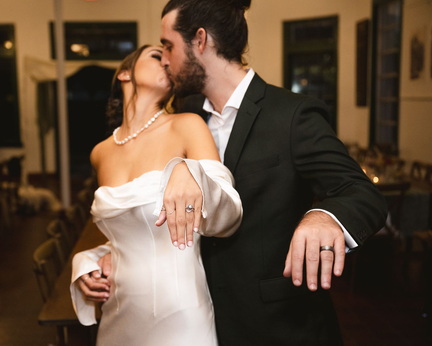 Intimate wedding moment showing matching wedding bands in an indoor setting.