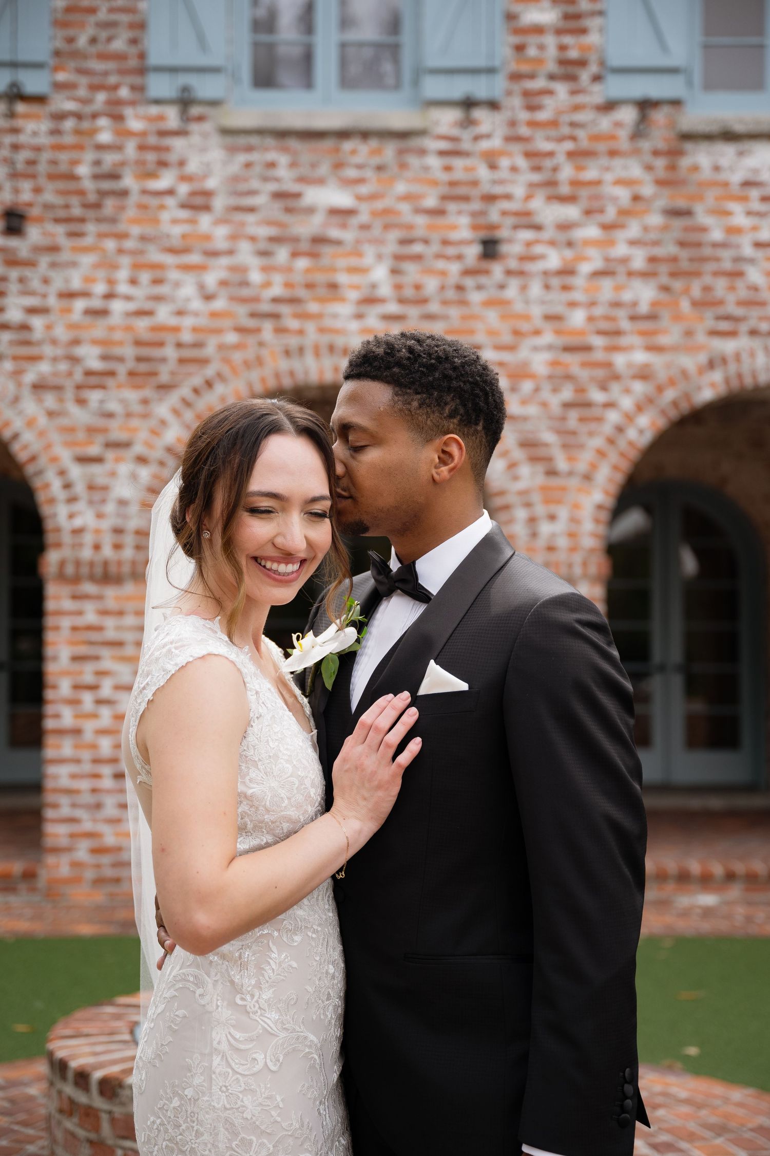 Romantic wedding portrait against a rustic brick archway and courtyard.