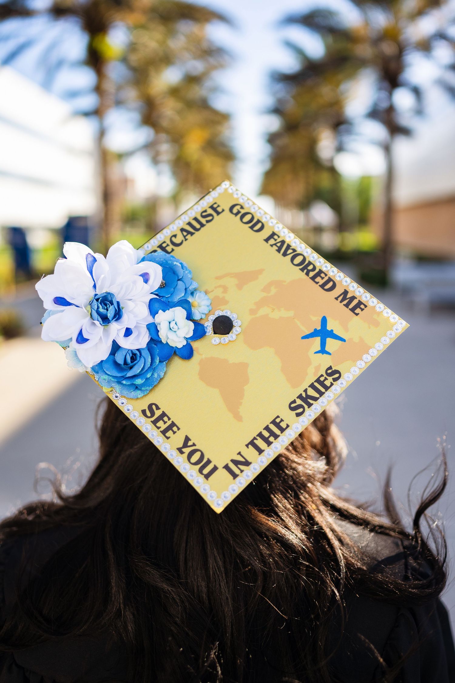Decorated graduation cap with blue flowers and inspirational message about flying high.