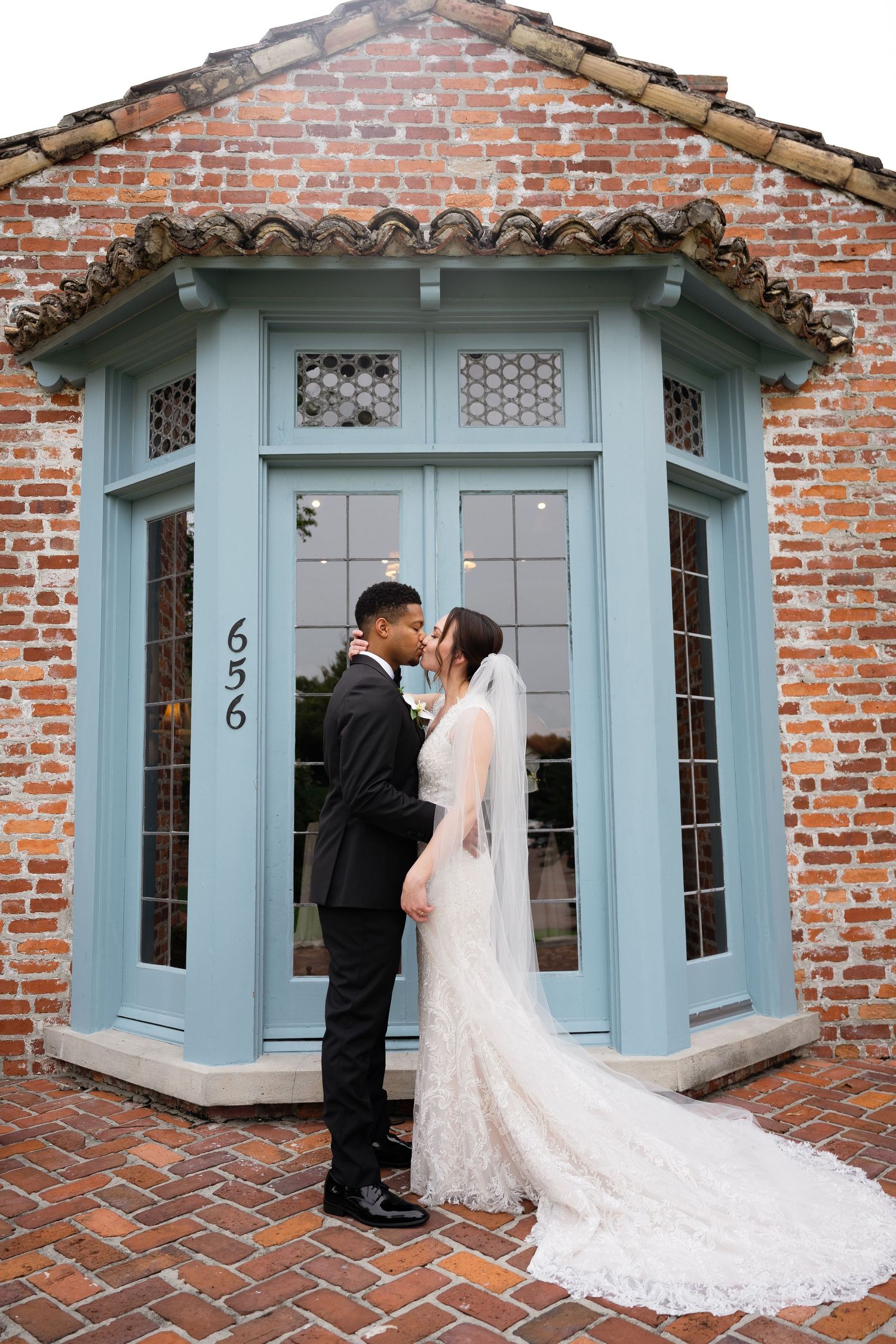A romantic wedding portrait in front of a blue-trimmed brick entrance.