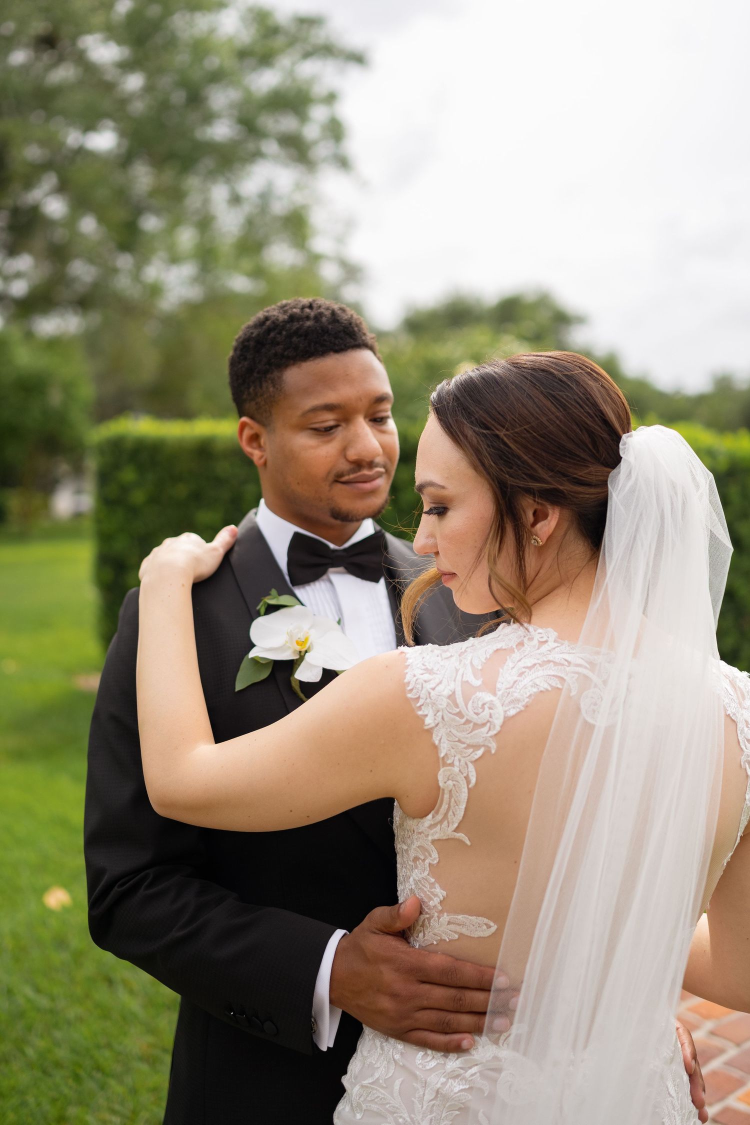 Newlyweds embrace in an intimate moment surrounded by lush garden greenery.