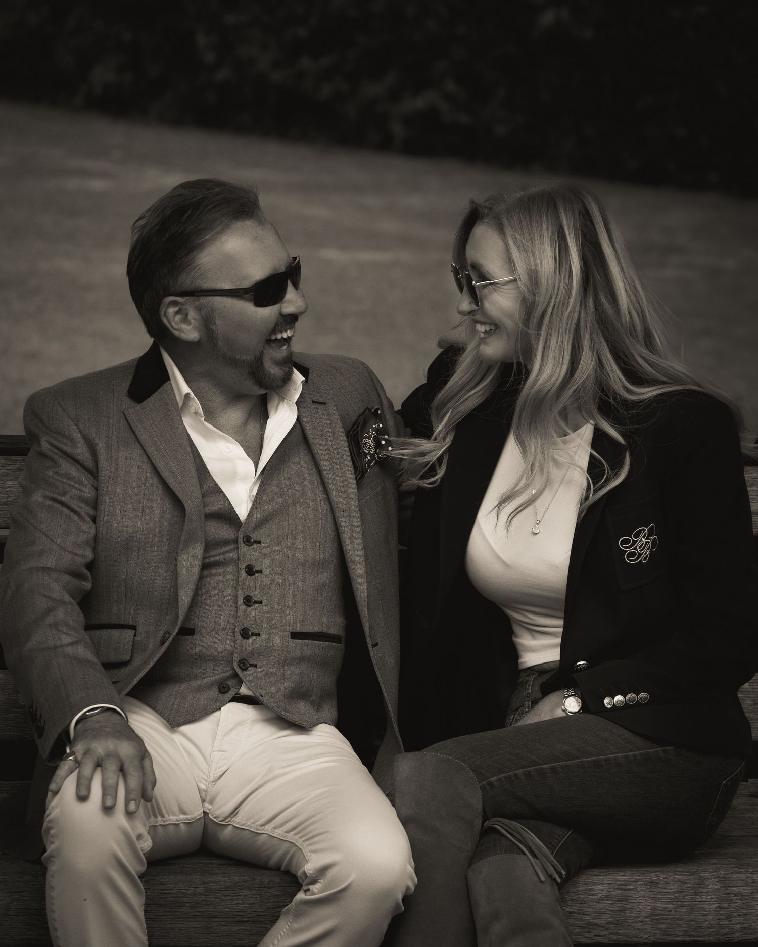 A couple shares an intimate moment on a bench in vintage-style black and white photography.