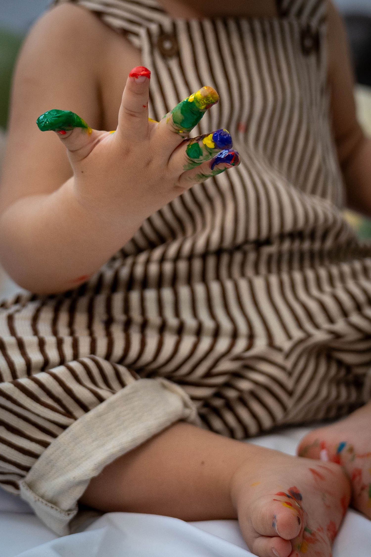 Small colorful toy dinosaurs rest on a striped blanket in a close-up shot.
