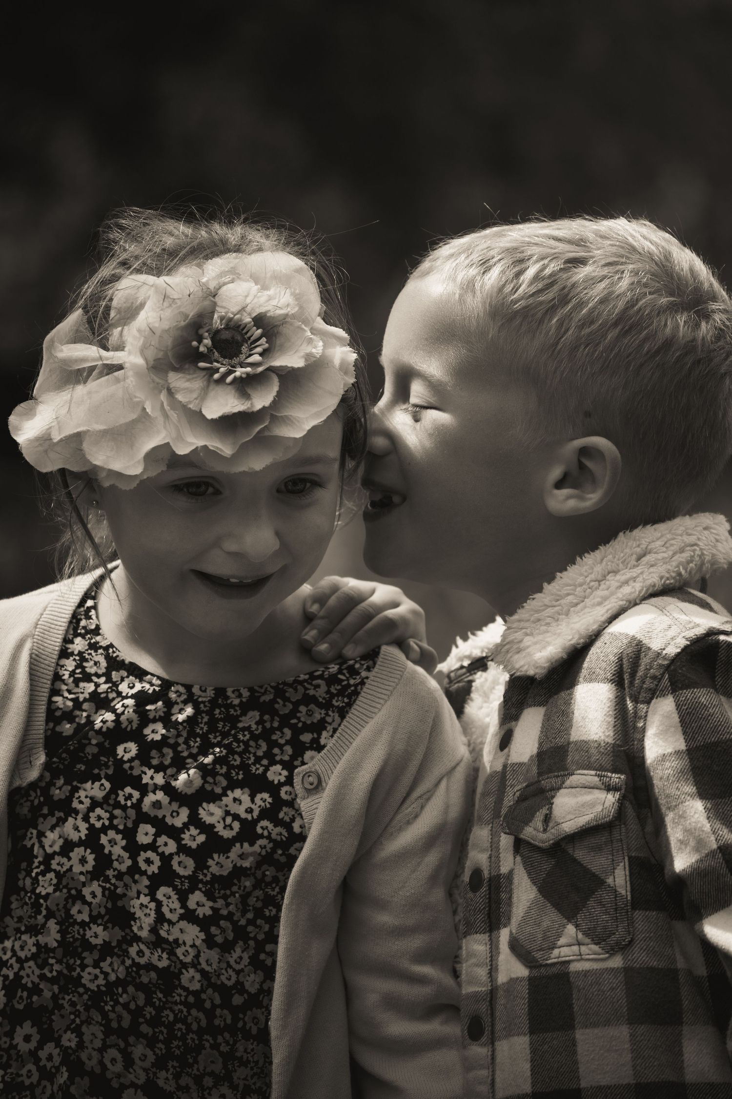 Children wearing plaid shirts share a playful moment in monochrome.