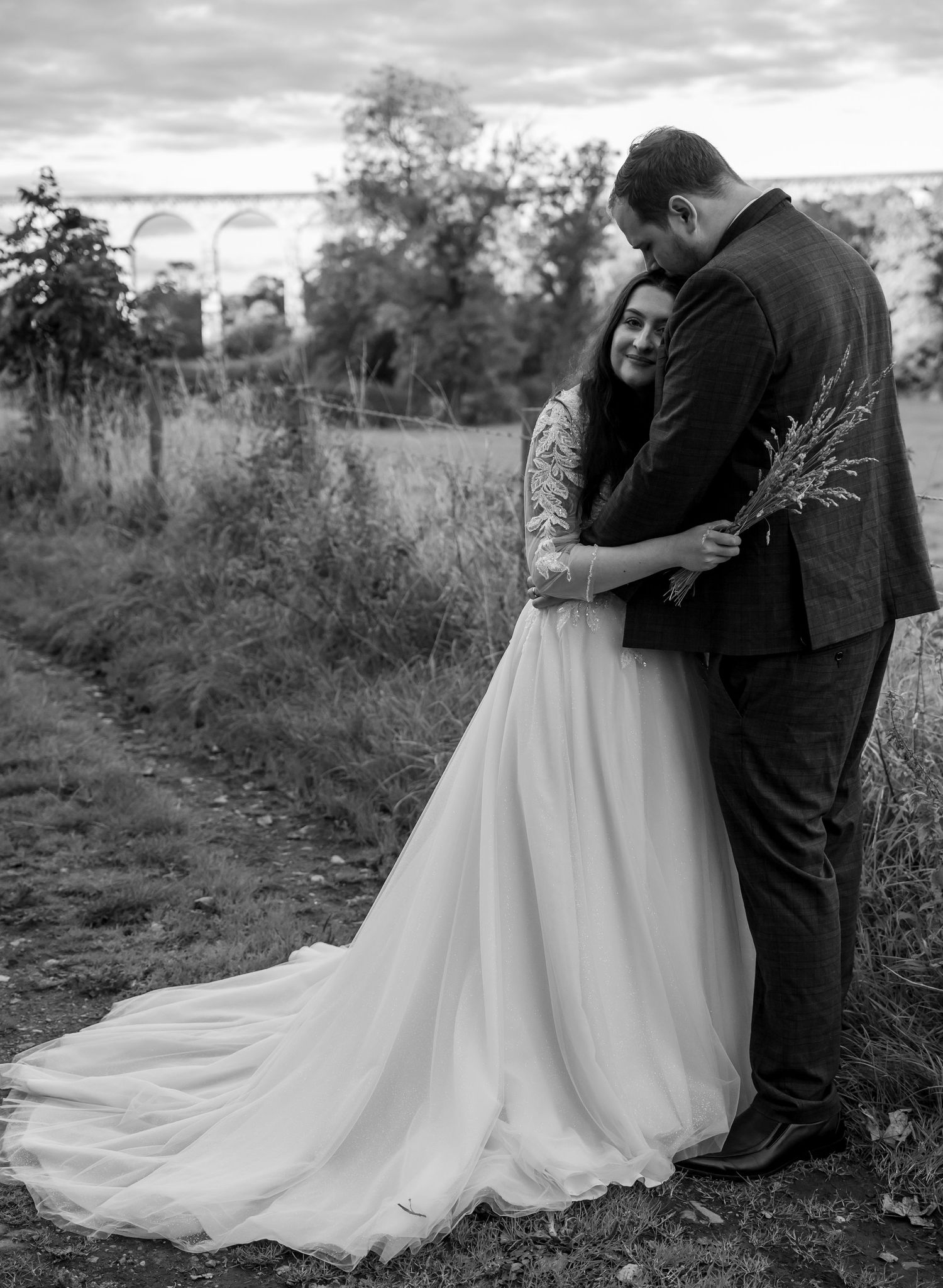 Romantic black and white wedding portrait in a scenic outdoor setting.