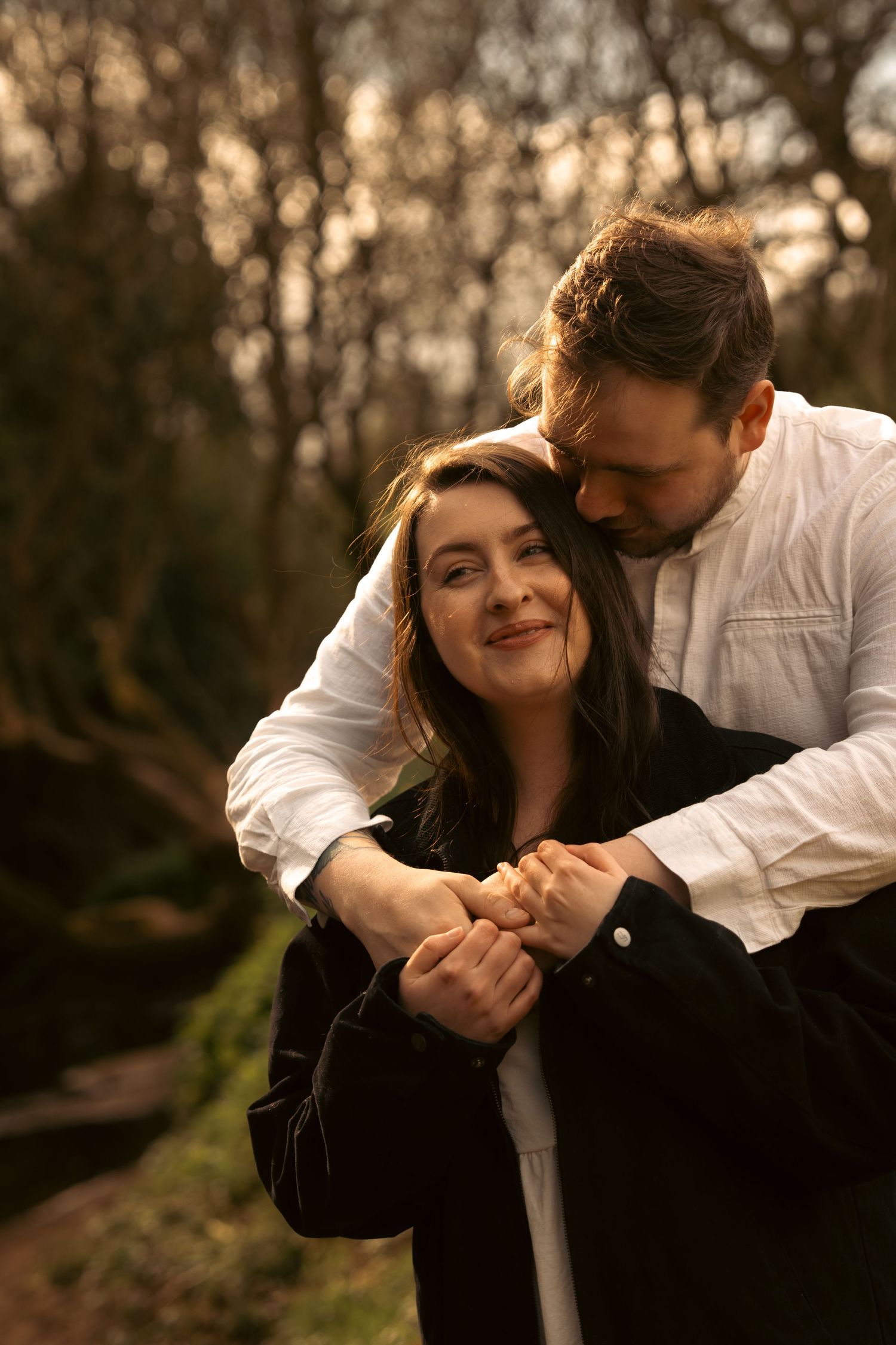 A tender embrace captured during a sunset photoshoot in the woods.