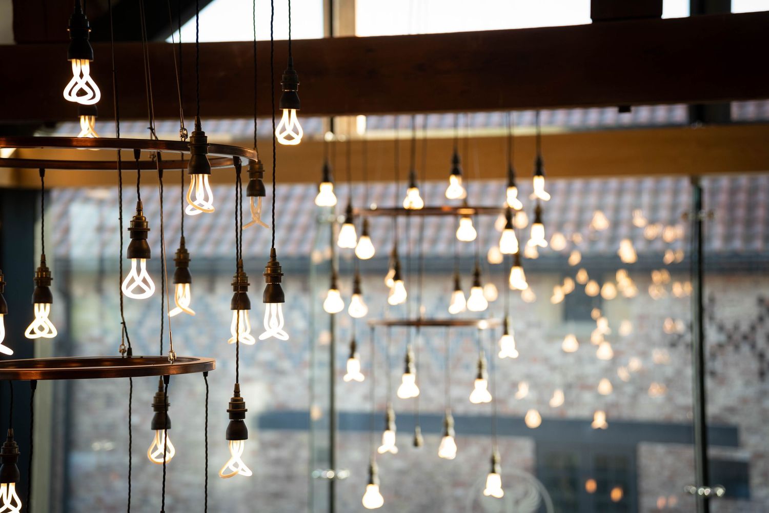 Rustic industrial cafe interior with hanging Edison bulb pendant lights creating warm ambient lighting against dark walls.